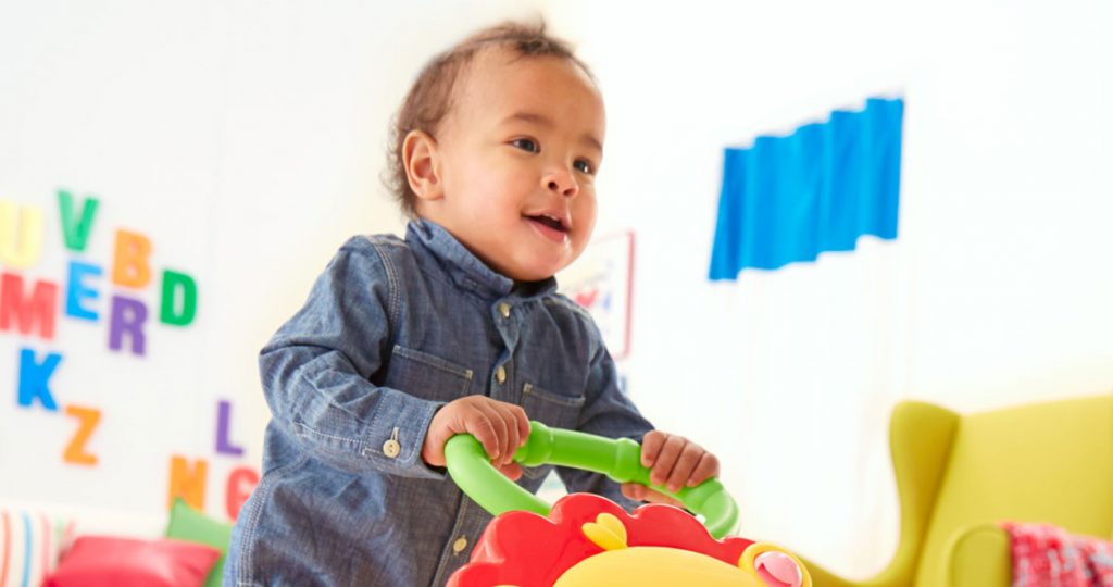 Bebê segurando carrinho com desenvolvimento da preensão propriamente dita